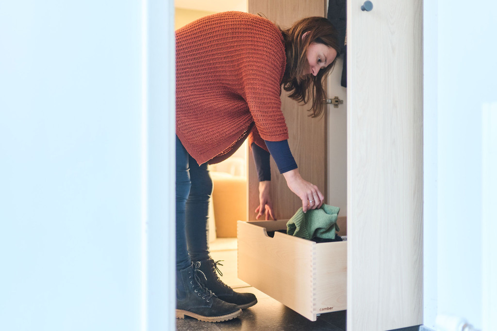 Vrouw haalt een trui uit een open lade van een maatkast in de vestiaire