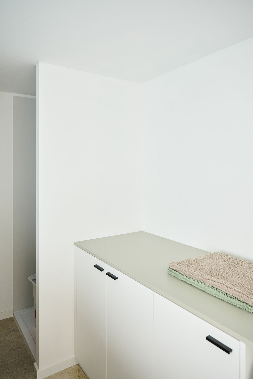 Plan de travail clair avec serviettes pliées sur des portes d’armoire blanches dans une buanderie moderne