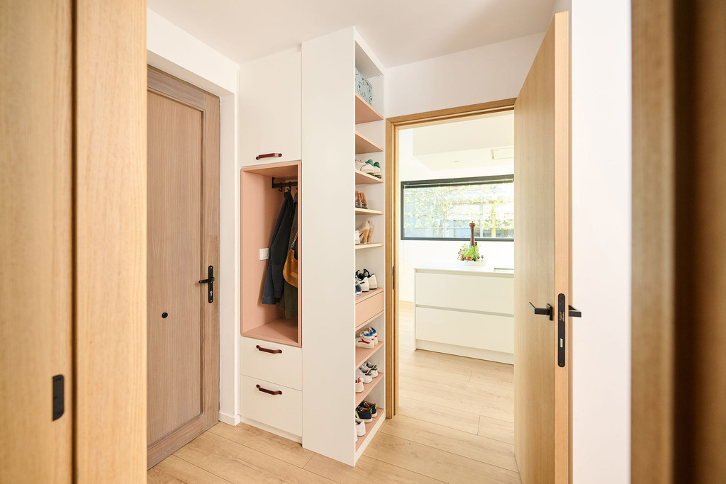 Vue d’ensemble d’une vestiaire Camber sur mesure dans le hall d’entrée, avec niche ouverte pour manteaux, rangement à chaussures, tiroirs intégrés et passage vers l’espace de vie dans un aménagement clair et fonctionnel