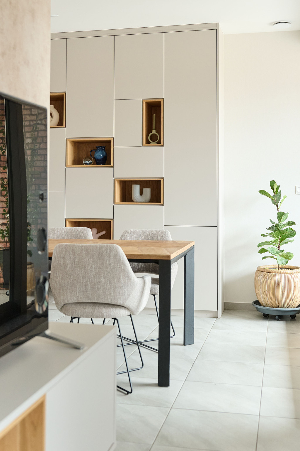 Maatkast met open houten vakken geïntegreerd in een eetruimte met tafel en stoelen, voor een combinatie van opbergruimte en decoratie