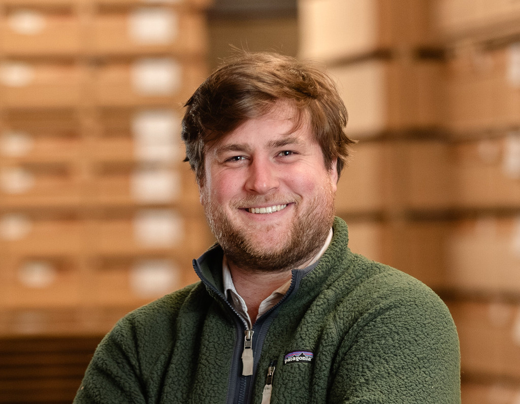 Portrait de Gauthier, Sustainability Project Manager chez Camber, dans l’usine de Chailley avec des panneaux de bois empilés en arrière-plan