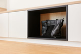 Meuble bas blanc avec compartiment ouvert pour sac en cuir noir.