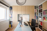 Thuisbureau met centraal bureau, houten maatwerkkasten en open boekenkasten aan beide zijden voor een grote boekencollectie