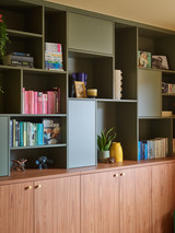 Wandkast met open en gesloten vakken in kaki en hout, ingericht met boeken en decoratie