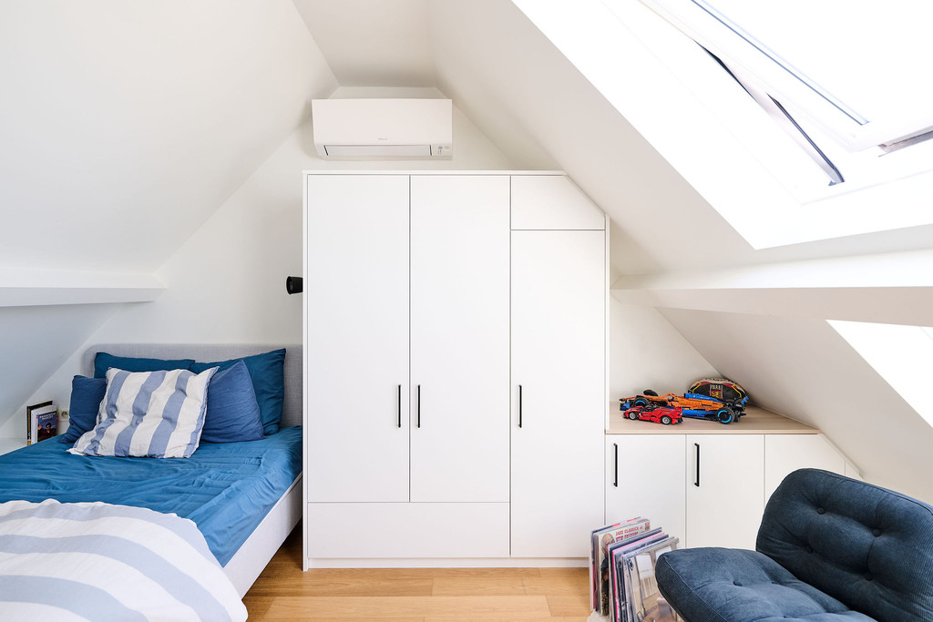 Placard sur mesure avec portes et rangements sous pente à côté d’un lit dans une chambre d’enfant