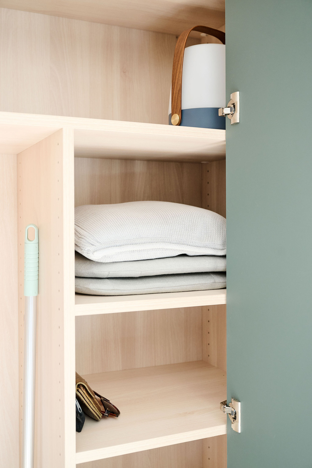 Armoire sur mesure avec porte ouverte et étagères contenant du linge de maison et une lampe nomade