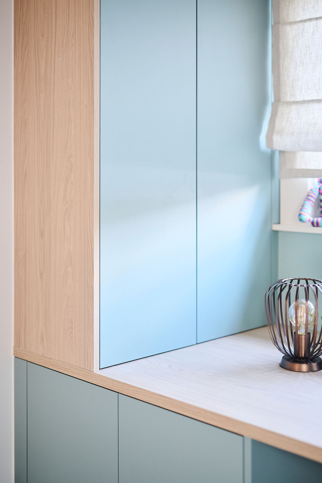 Kast in lichtblauw en hout met gesloten deuren op maat boven bureau met decoratieve lamp