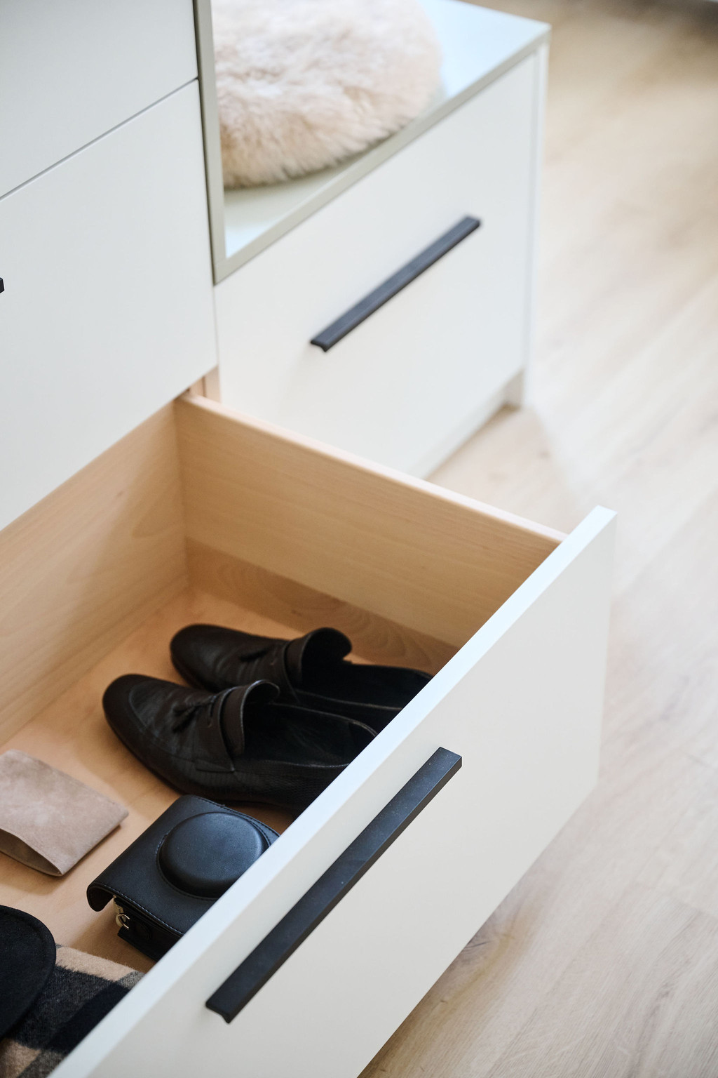 Open witte lade met houten binnenkant en zwarte herenschoenen in een op maat gemaakte dressingkast