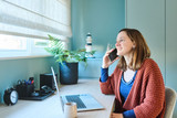 Vrouw aan bureau op maat met laptop plant en blauw kastvolume in lichtrijke werkruimte