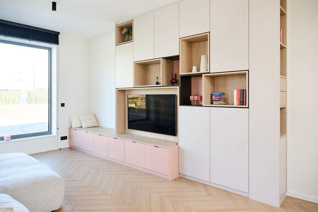 Meuble TV sur mesure avec assise intégrée, niches ouvertes en bois et rangements fermés dans un salon lumineux