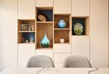 Detail van een wandmeubel op maat met witte fronten, open houten nissen in verschillende formaten en geïntegreerde lades