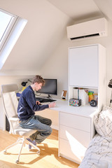 Bureau sur mesure avec placard intégré sous pente utilisé par un adolescent dans une chambre