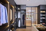 Dressing sur mesure avec penderie, niches ouvertes et éclairage LED intégré en bois foncé dans un showroom