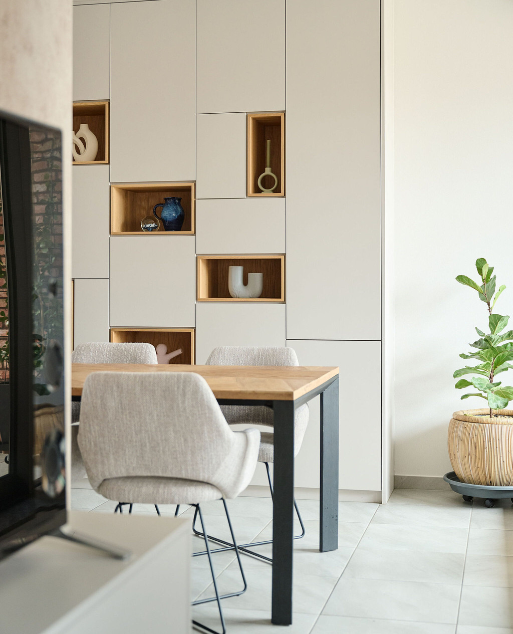 Placard sur mesure avec niches ouvertes en finition bois, intégré dans une salle à manger avec table et chaises, alliant rangement et décoration, réalisé par Camber