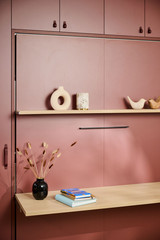 Bureau sur mesure avec tablette rabattable, étagère décorée avec des objets modernes et vase, créant un espace de travail élégant.