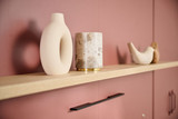 Étagère décorative en bois avec des objets d'art et des vases modernes, mise en valeur sur un fond rose doux.