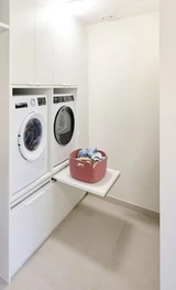 Buanderie sur mesure avec machine à laver et sèche-linge encastrés, tablette dépliable et meubles de rangement intégrés.