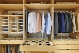 Kledingkast op maat in U-vorm met hangruimte voor kleding, lades voor accessoires en opbergvakken voor georganiseerd gebruik.