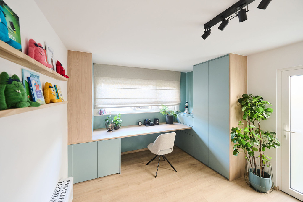 Op maat ingericht bureau met blauwe kasten houten accenten en kindvriendelijke boekenplanken na renovatie