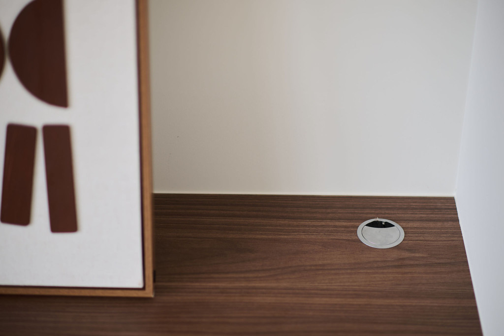 Détail du plateau en bois avec passe-câble intégré dans un meuble TV sur mesure