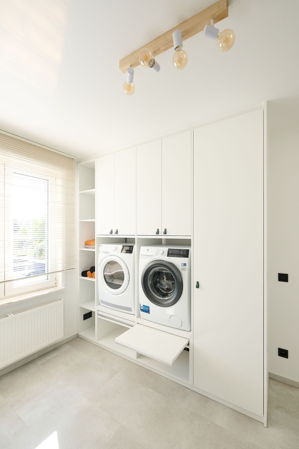 Colonne sur mesure blanche avec lave-linge et sèche-linge intégrés dans une buanderie lumineuse