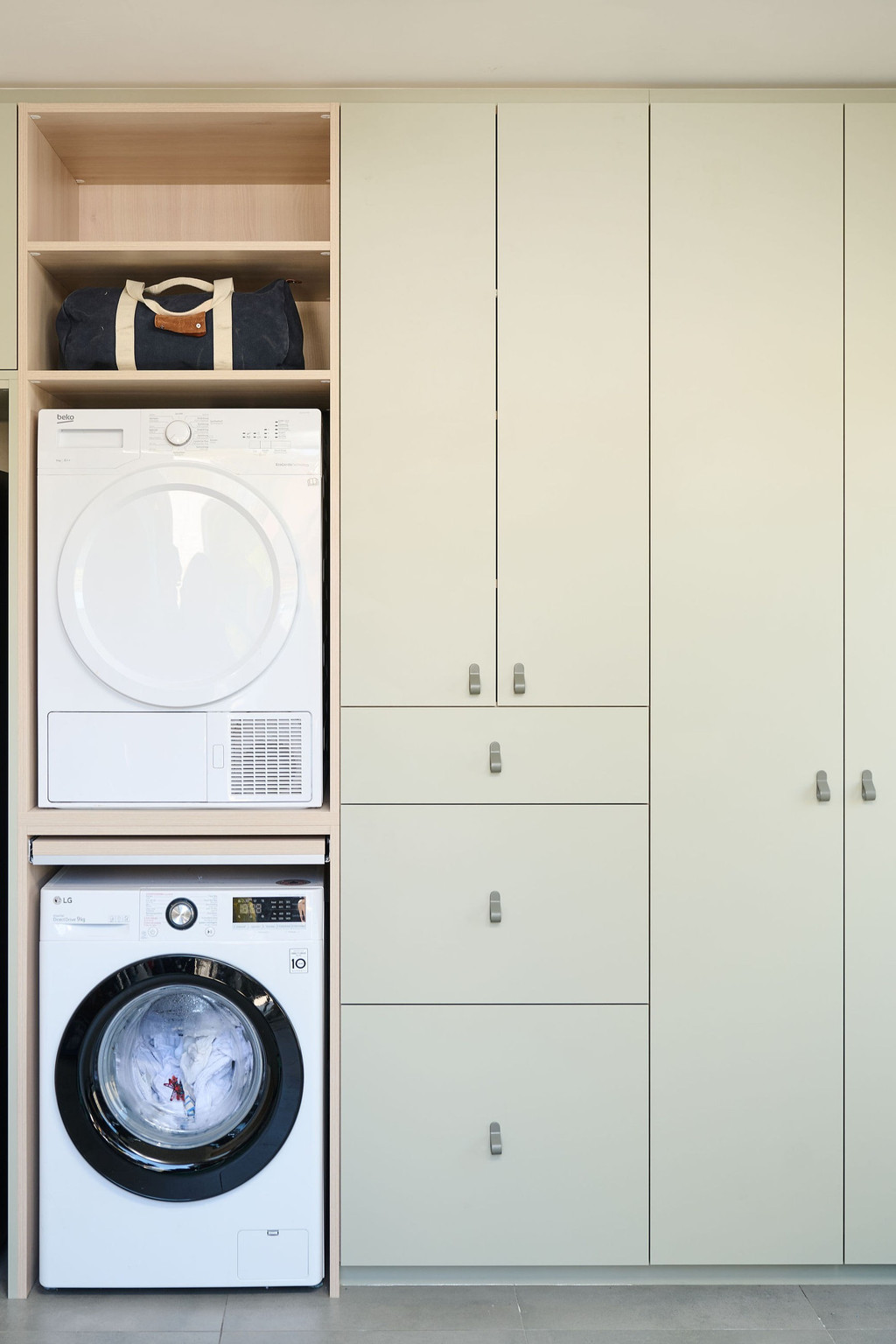 Wasruimte op maat met ingebouwde wasmachine en droogkast, gesloten kasten en legplanken, voor een praktische en georganiseerde indeling