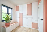 Dressing sur mesure avec des éléments blancs et rose, incluant un banc intégré et des étagères de rangement.