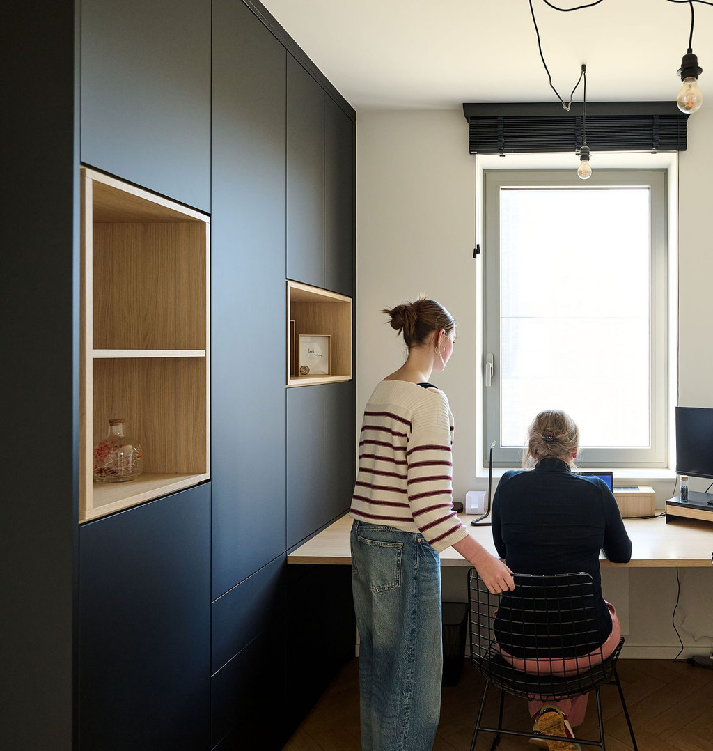 Bureau à domicile sur mesure avec armoires noires et niches ouvertes en décor bois, deux femmes travaillant près de la fenêtre