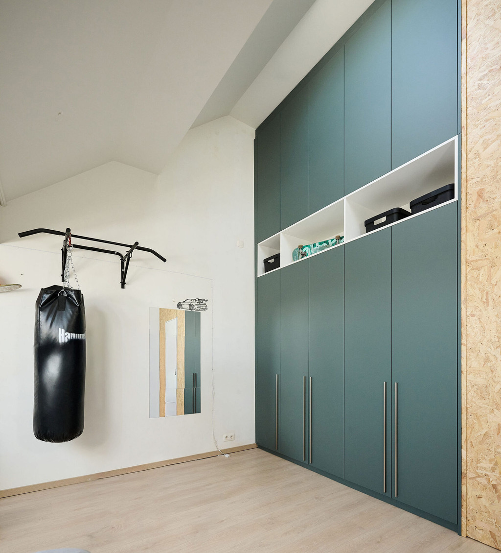 Resultaat na de inrichting van een jongenskamer in Hemiksem met een inbouwkast op maat onder een schuine wand, uitgevoerd in groene kastfronten met geïntegreerde opbergnissen