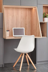 Bureau sur mesure avec niche en bois et espace de rangement intégré, équipé d'un ordinateur portable et d'une chaise blanche.