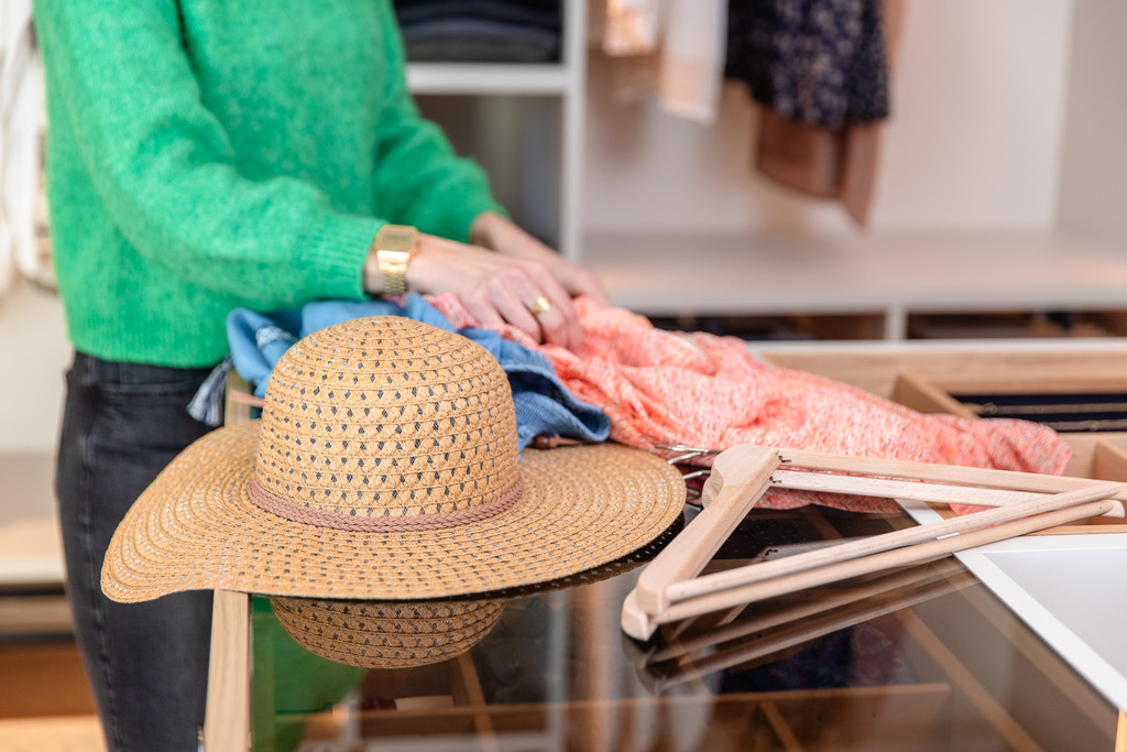 Tiroir ouvert avec accessoires et vêtements d'été dans dressing sur mesure avec séparation en bois et plateau en verre