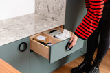 Open lade op maat met georganiseerde accessoires en afstandsbediening in een moderne groene kast.