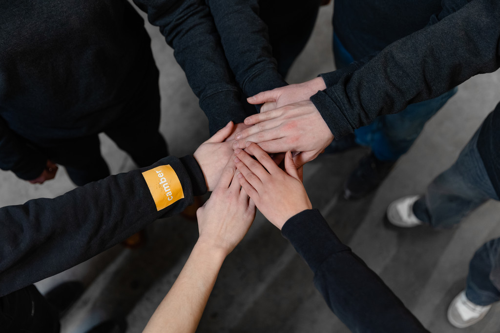 Medewerkers die hun handen samenbrengen als symbool voor solidariteit en het engagement van Camber.