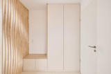 Meuble d'entrée sur mesure avec une banquette intégrée en bois clair et un mur à lattes de bois décoratif.