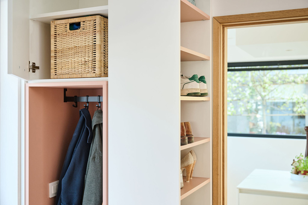 Détail d’une vestiaire Camber sur mesure avec niche ouverte pour manteaux, patères intégrées, étagères pour chaussures et accessoires, et finitions claires et épurées
