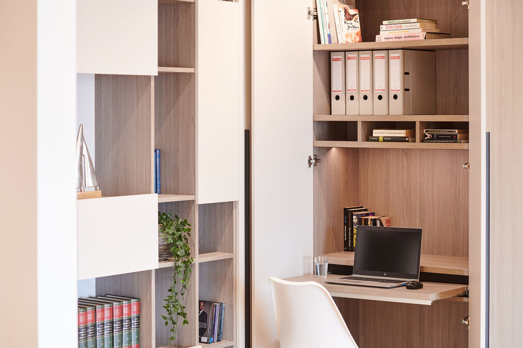 Bureau sur mesure avec rangement intégré, étagères ouvertes et espace de travail minimaliste avec ordinateur, offrant un aménagement fonctionnel.