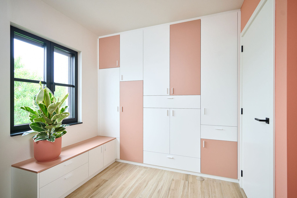 Dressing en L sur mesure avec des niches colorées et un banc intégré, offrant une solution de rangement moderne et fonctionnelle.