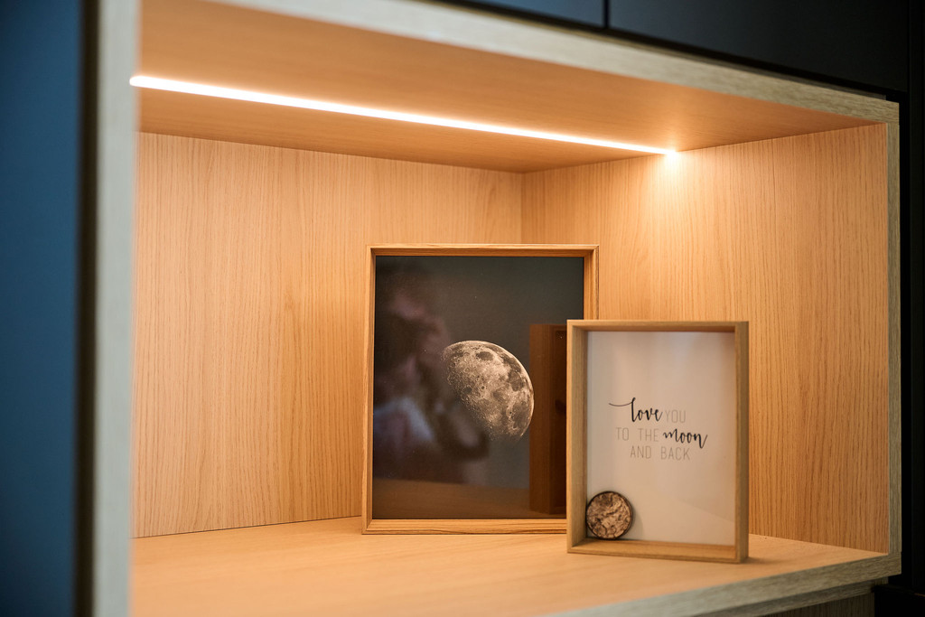 Decoratieve nis in licht hout met ingebouwde LED-verlichting en fotokaders op de plank