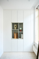 Vestiaire blanche sur mesure avec niches ouvertes pour décoration et livres dans une pièce lumineuse