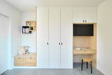 Chambre d'enfant sur mesure avec mobilier blanc, étagères et bureau intégré avec coussin et jouet.