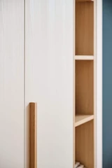 Detail van een witte dressingkast op maat met een houten greep en open vakken in natuurlijke houtafwerking.