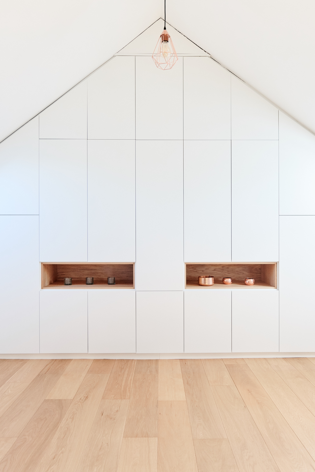 Dressing sur mesure sous pente avec portes blanches, niches en bois et éclairage naturel.
