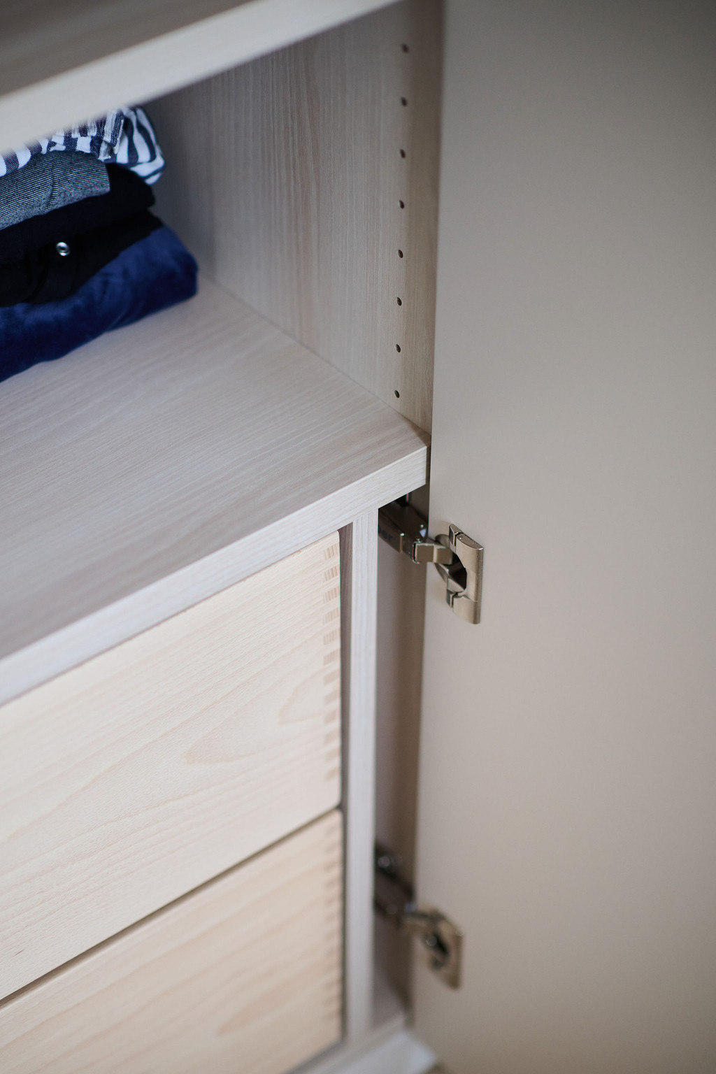 Détail d’une armoire sur mesure ouverte avec tiroir intégré et charnière métallique