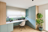 Bureau en L sur mesure avec éléments bleus et bois sous fenêtre dans une pièce lumineuse avec touches vertes