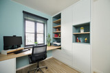 Bureau sur mesure avec bibliothèque intégrée, rangements fermés et niches ouvertes, avec mur vert d’eau et grand bureau en bois.