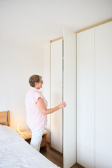 Anne opent een witte kledingkast op maat in de slaapkamer met een geïntegreerde spiegel en houten details