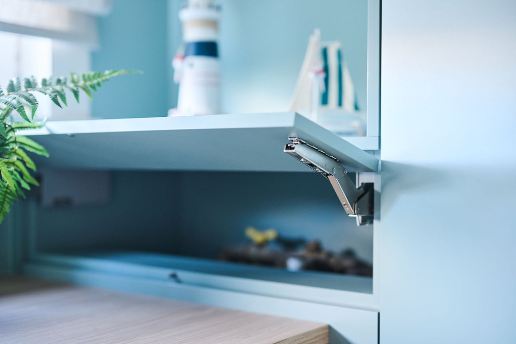 Gros plan sur un abattant bleu ouvert avec espace de rangement et détails décoratifs dans un bureau sur mesure