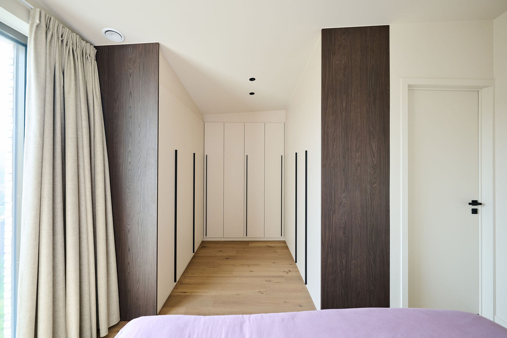 Dressing sur mesure en U avec portes en tons clairs, longues poignées noires et panneaux latéraux en bois foncé, offrant un espace structuré et élégant, réalisé par Camber