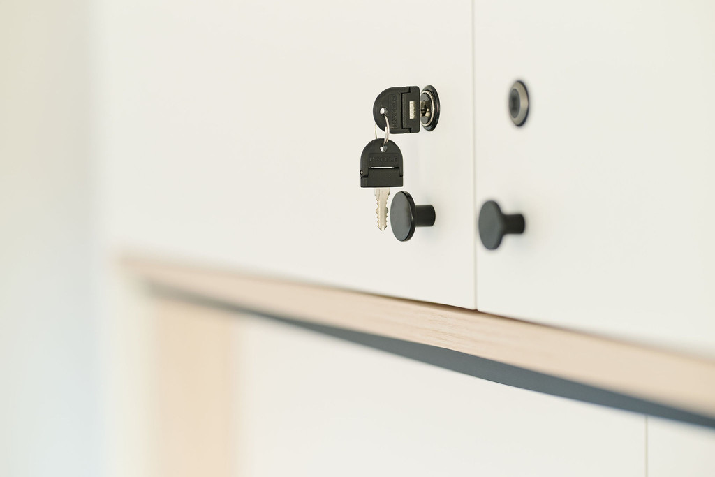 Gros plan sur une clé noire dans une porte blanche de meuble sur mesure