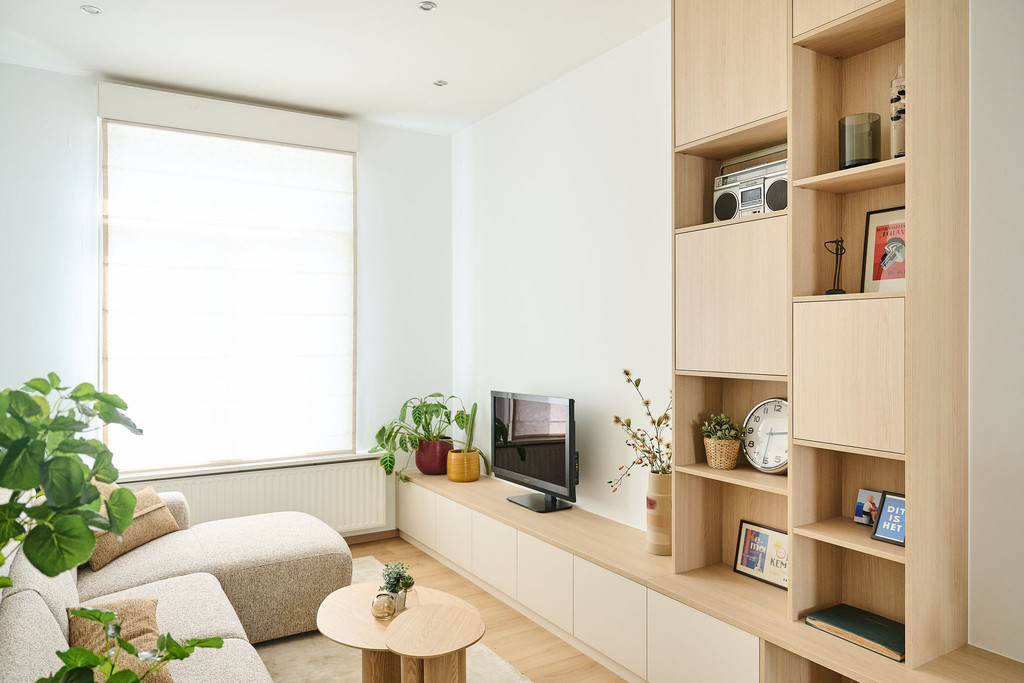 Meuble sur mesure avec niche pour télévision et étagères ouvertes décorées dans un salon clair
